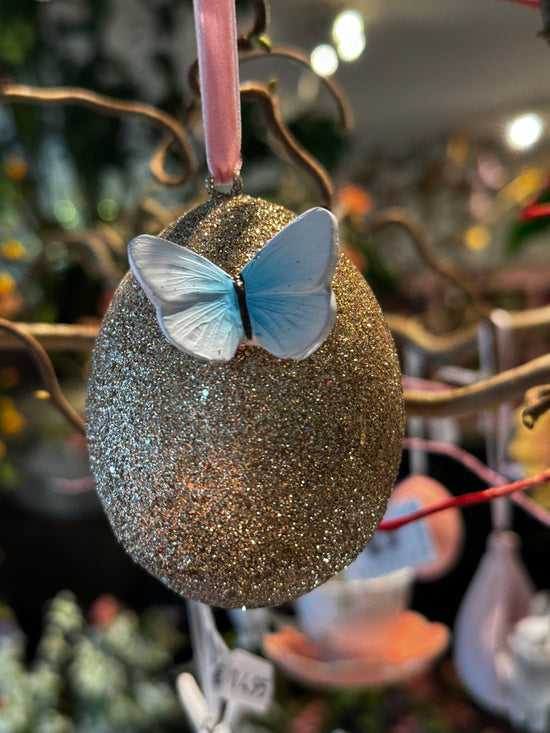 Gouden glitter paasei met blauwe vlinder